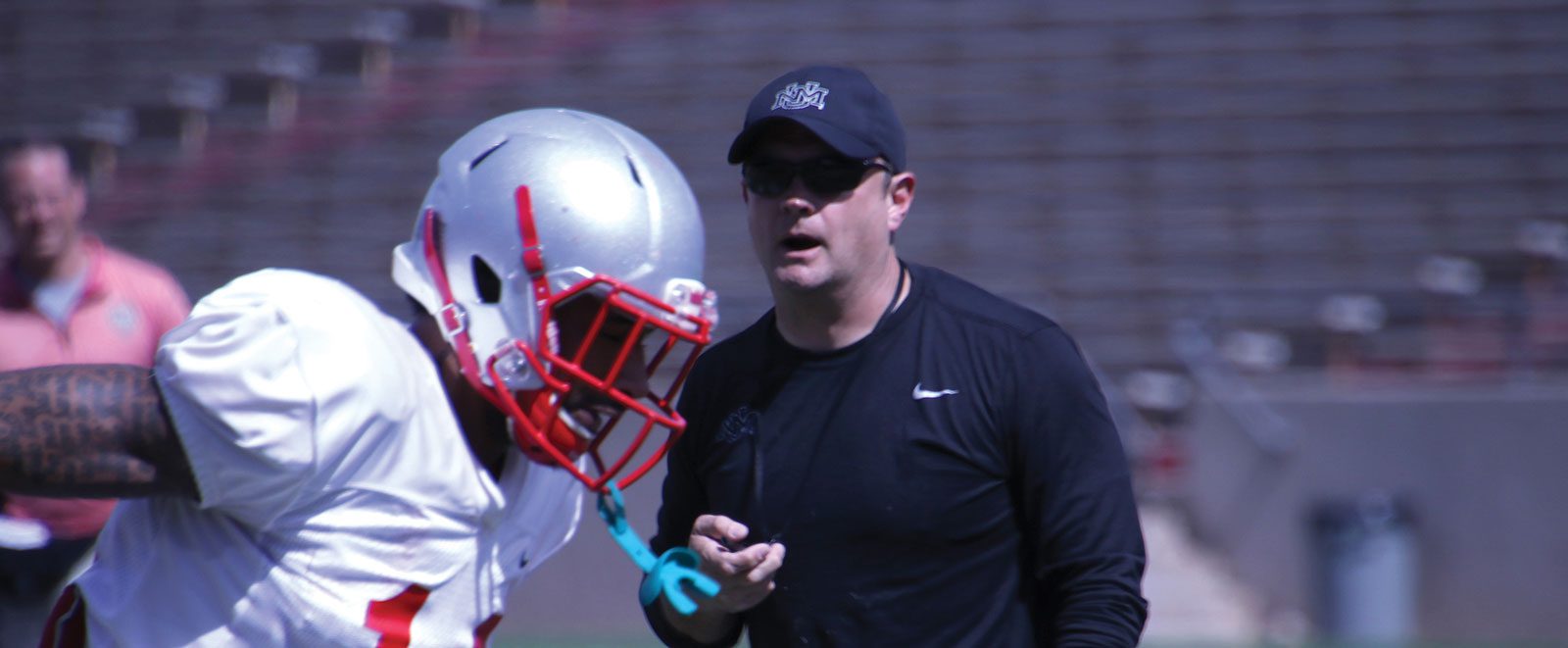 Coach Danny Gonzales with a Lobo Football player running in front of him