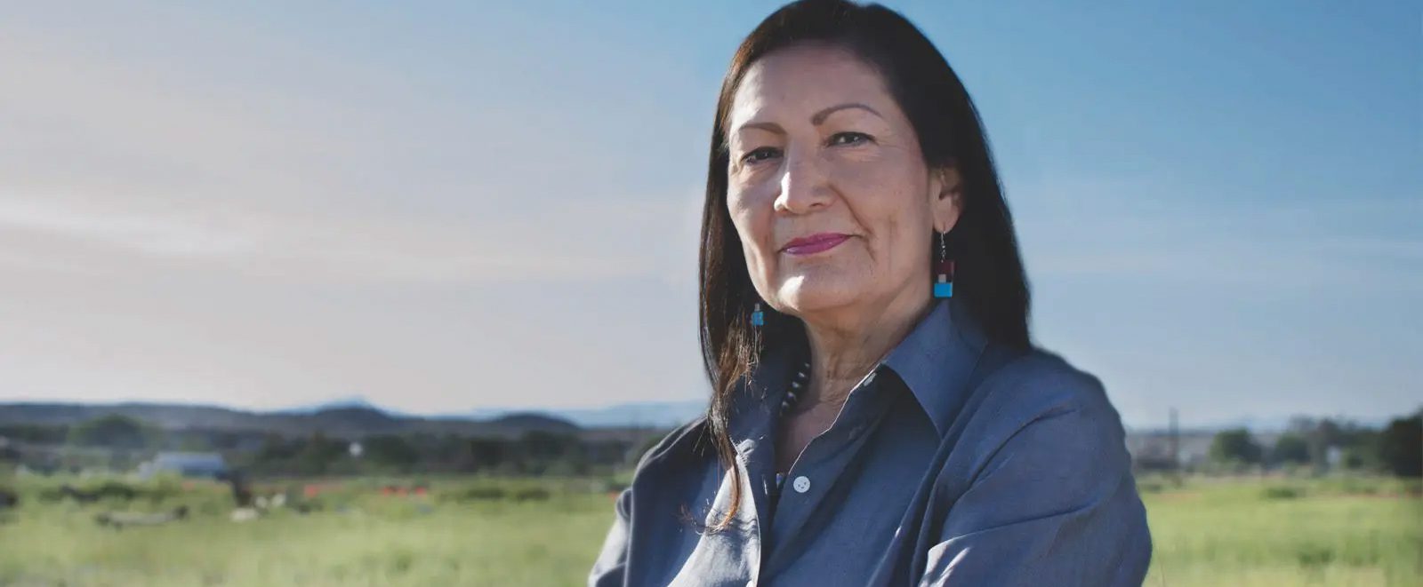 deb-halland-banner Deb Haaland standing cross armed outside in northern New Mexico