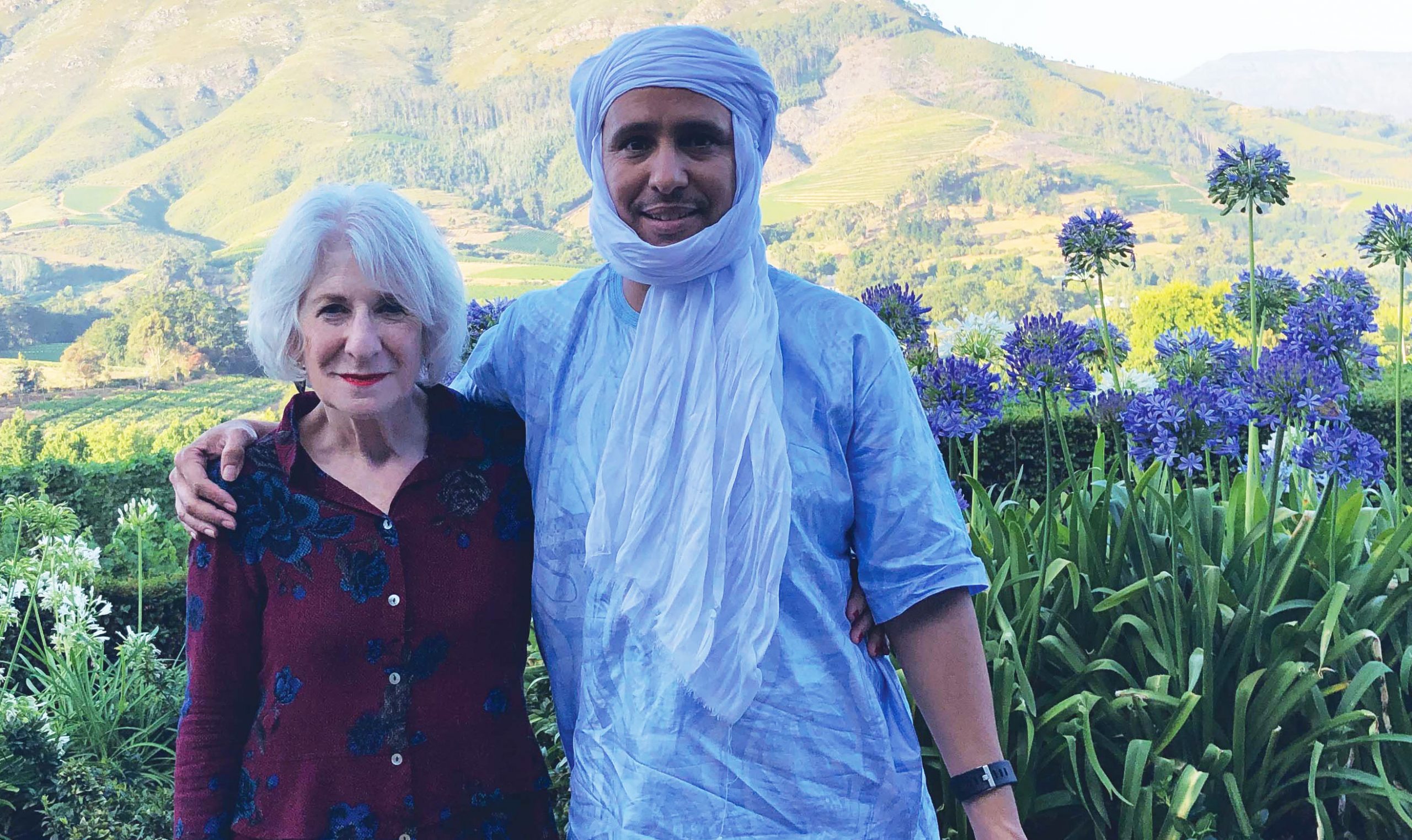 Nancy Hollander with Mohamedou Salahi outdoors in a lush, green environment
