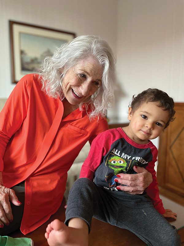 Nancy Hollander wearing an orange long sleeve button up shirt with Ahmed Salahi, Mohamedou Salahi’s son and her godson