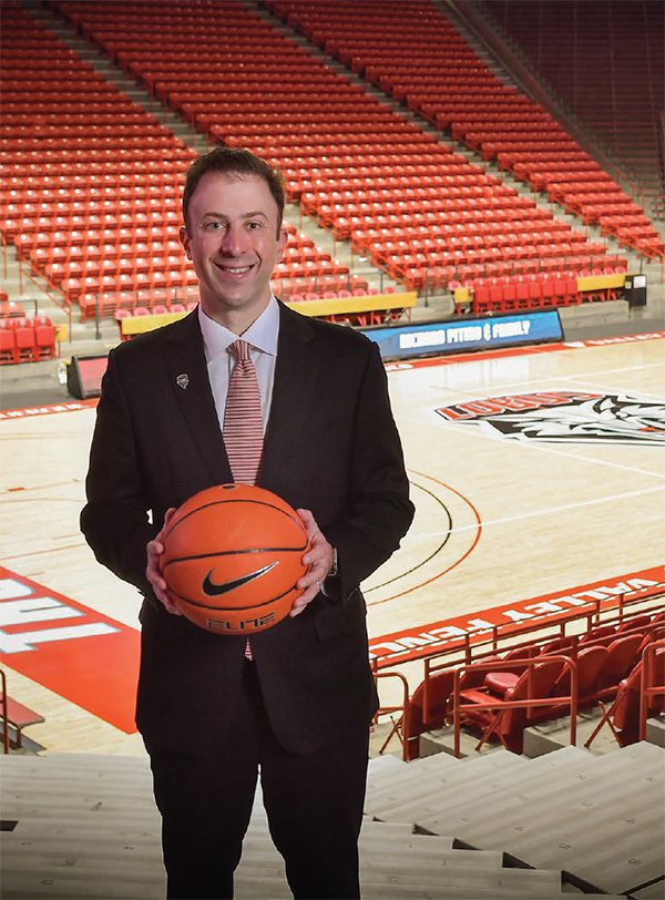 Richard Pitino holding a basketball with the Pit arena court behind him