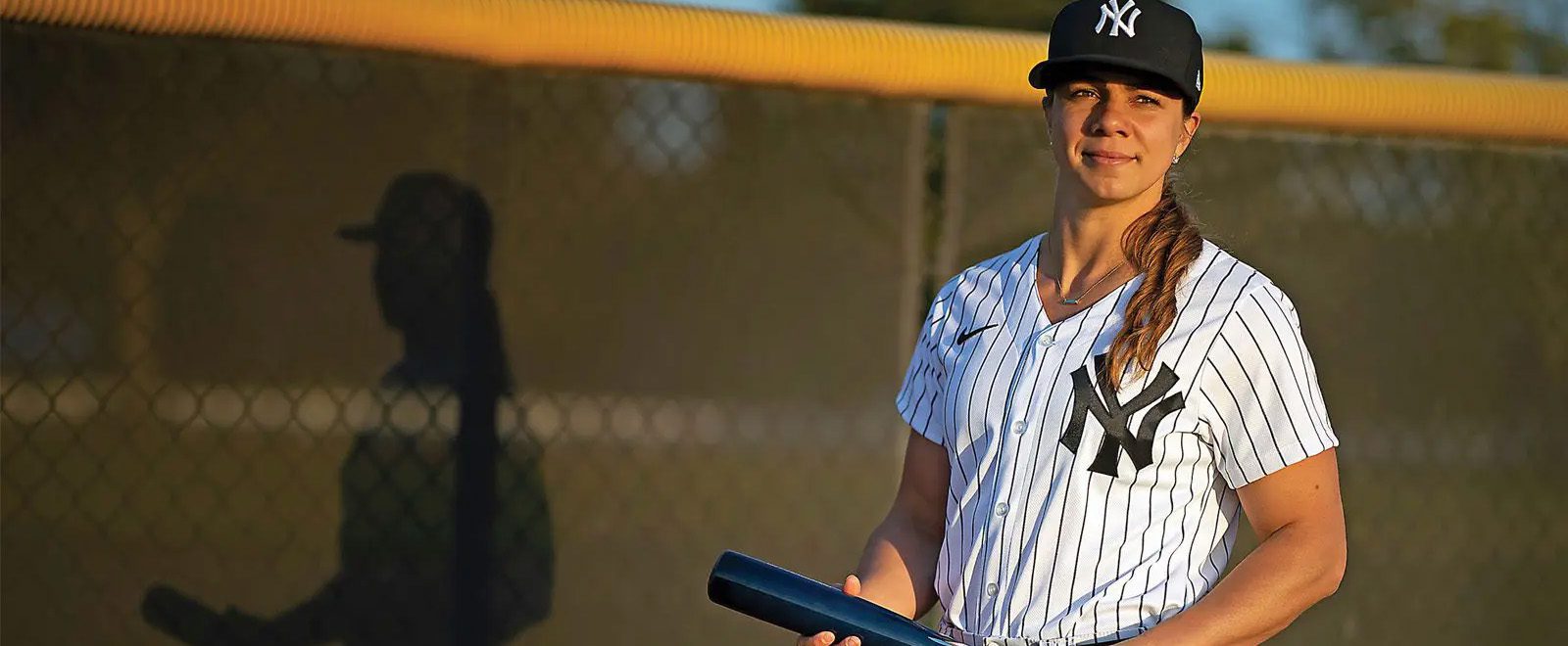 Rachel Balkovec holding a baseball bat dressed in New York Yankee uniform