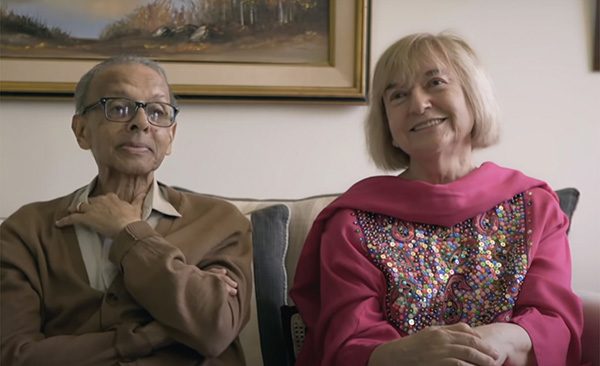 Nasir Ahmed and his wife Esther sitting on a couch smiling