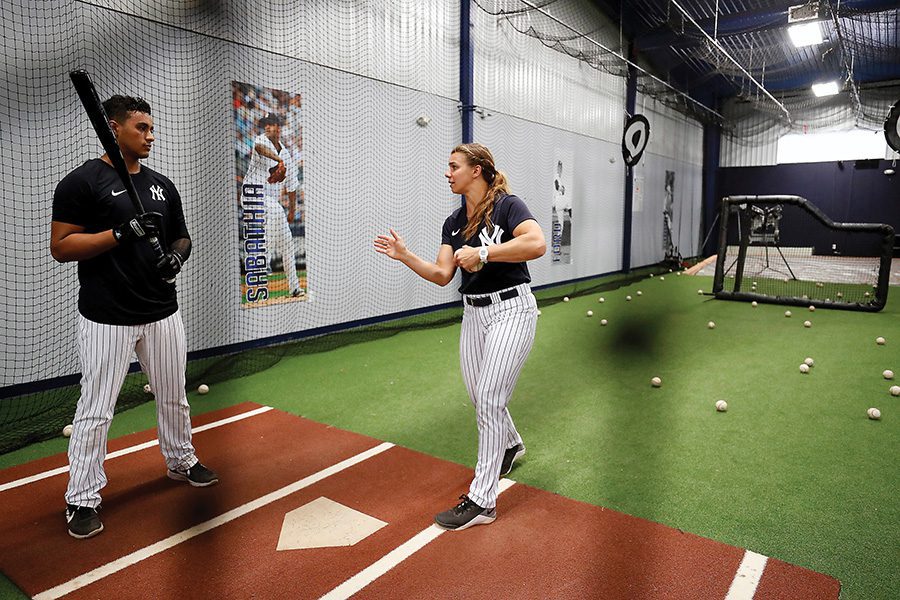 Rachel coaches a yankee player on hitting in the batting cage