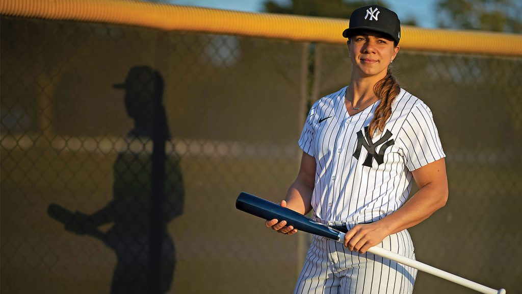 Rachel Balkovec holding a baseball bat dressed in New York Yankee uniform