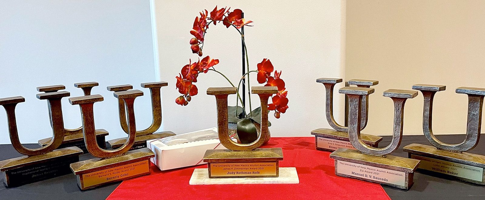 UNM Alumni award trophies on a red tablecloth