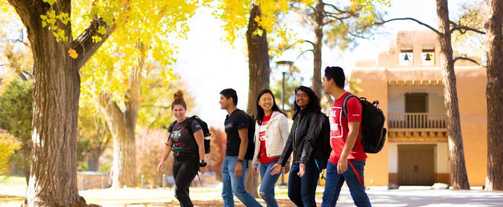UNM students walking on campus under fall leaves