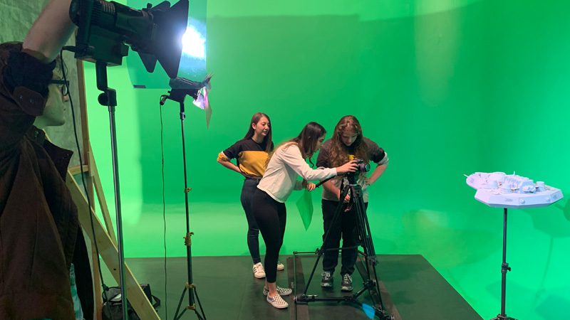 Film students collaborating on a project in front of a green screen
