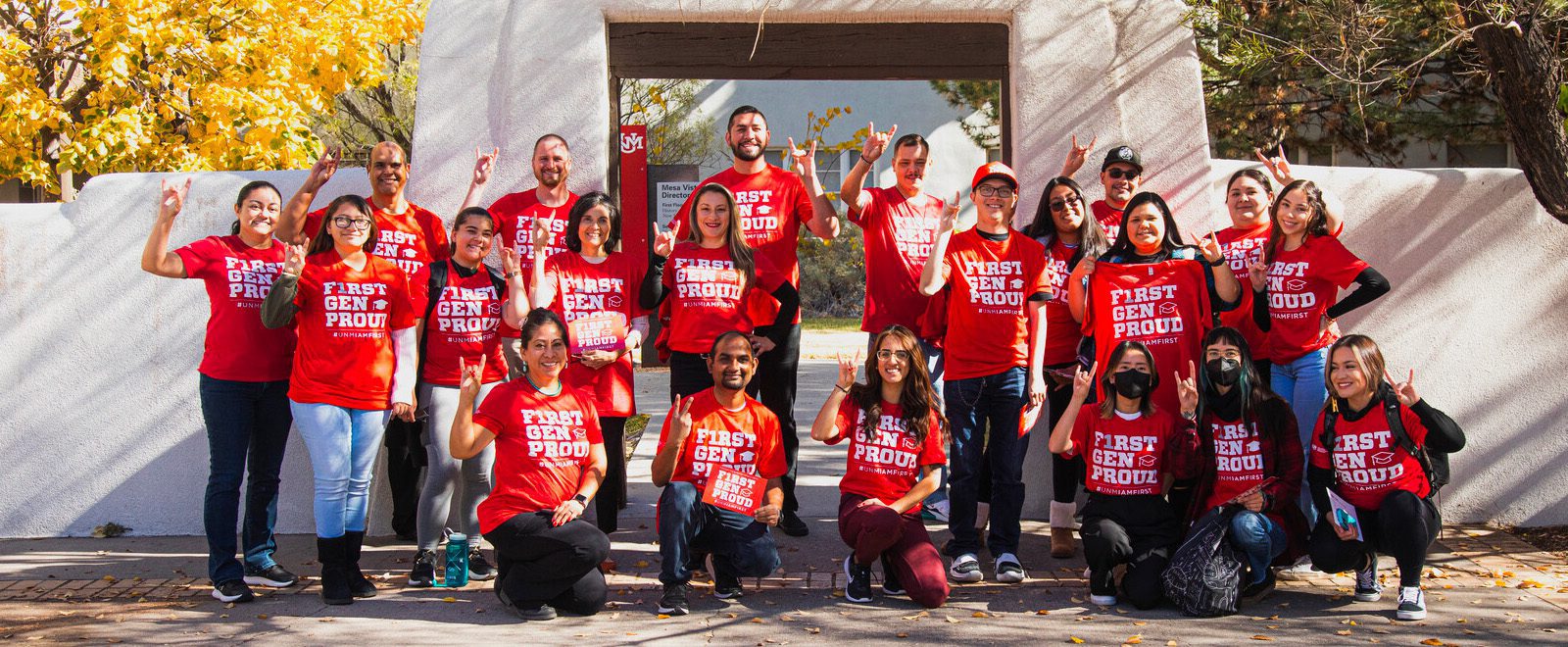 A group of first generation lobo proud students wearing matching shirts and posing on campus for the camera