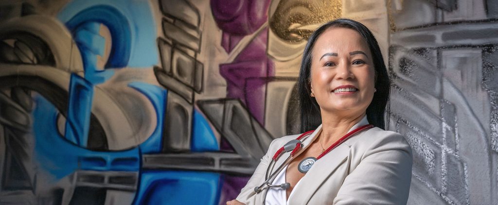 Tina Bui-Burgos smiling in front of painted mural